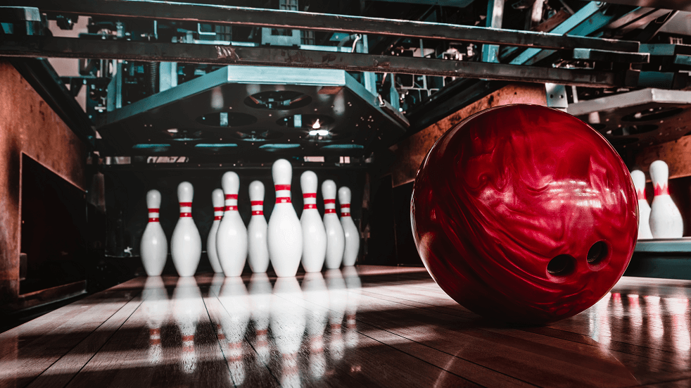red Bowling ball in front of 10 skittles all lined up